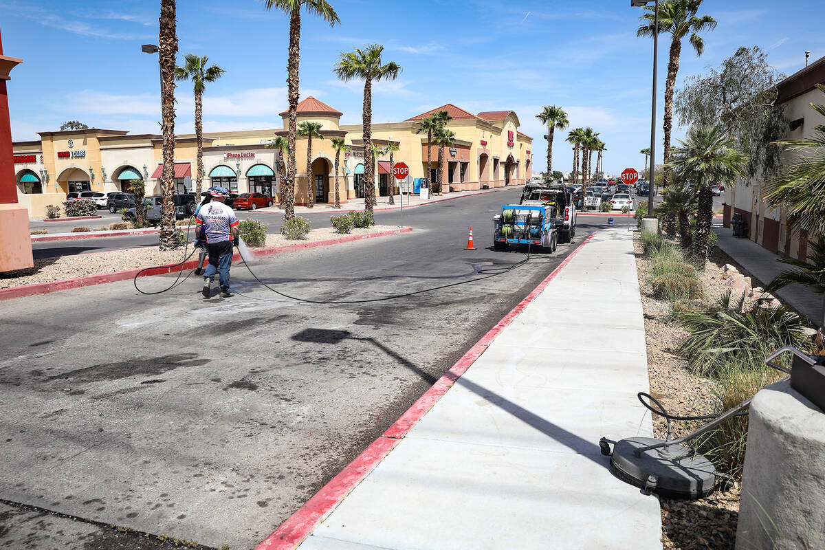 Workers clean the street from a fatal car crash near a strip mall at South Durango Drive and We ...