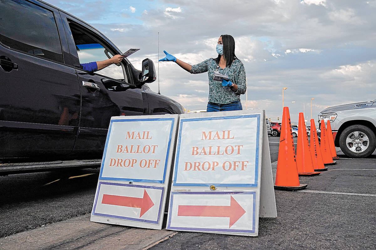 FILE - In this Nov. 2, 2020, file photo, a county worker collects mail-in ballots in a drive-th ...