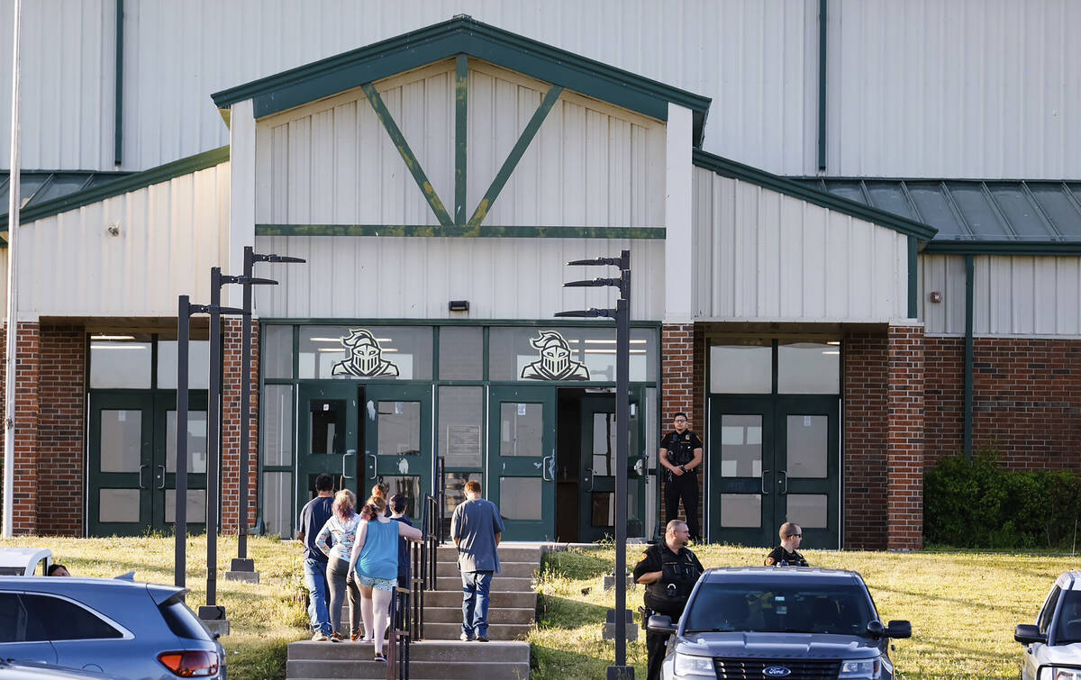 Law enforcement stand outside of Henryetta High School as people arrive for a vigil after Okmul ...