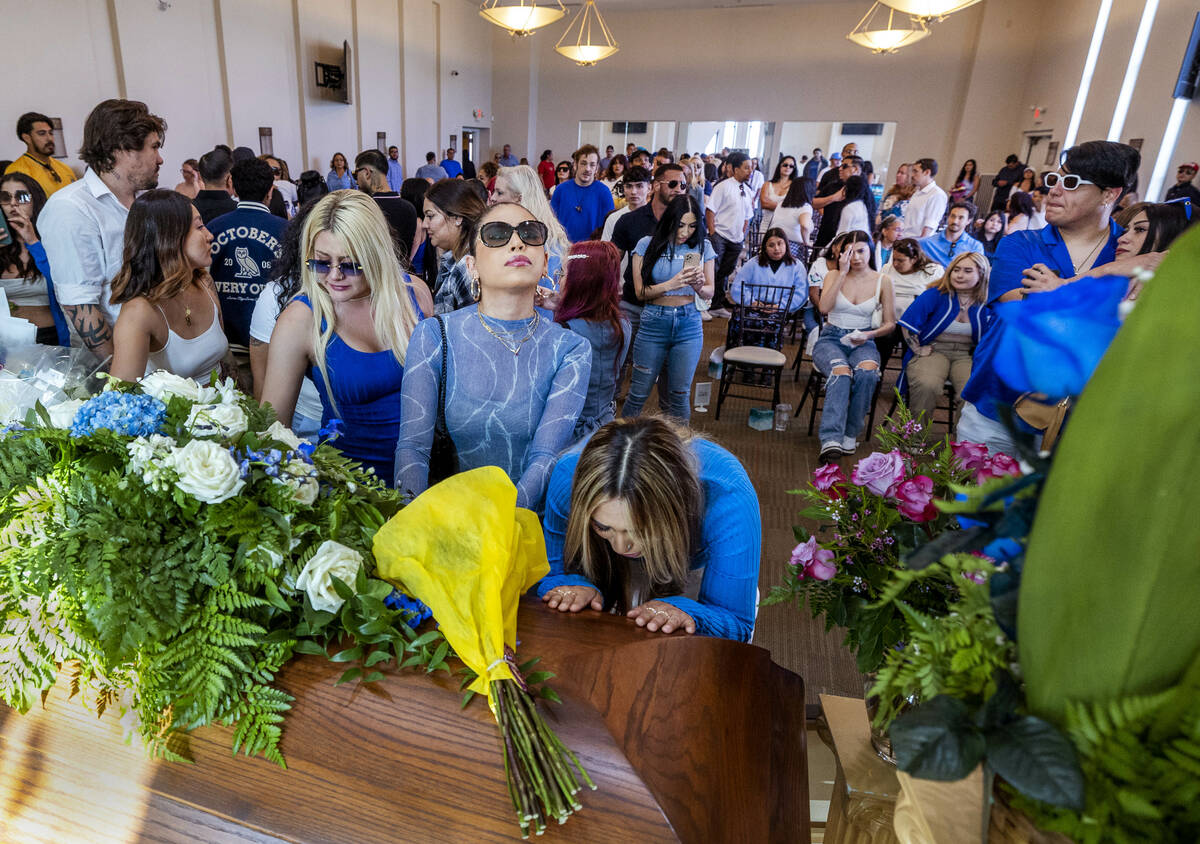 Friends and family members comfort each other and say their final goodbyes during a funeral ser ...