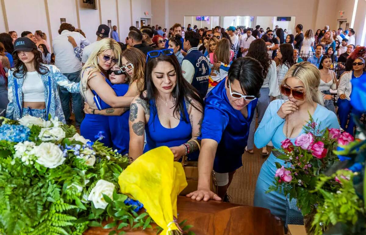 Friends and family members comfort each other and say their final goodbyes during a funeral ser ...