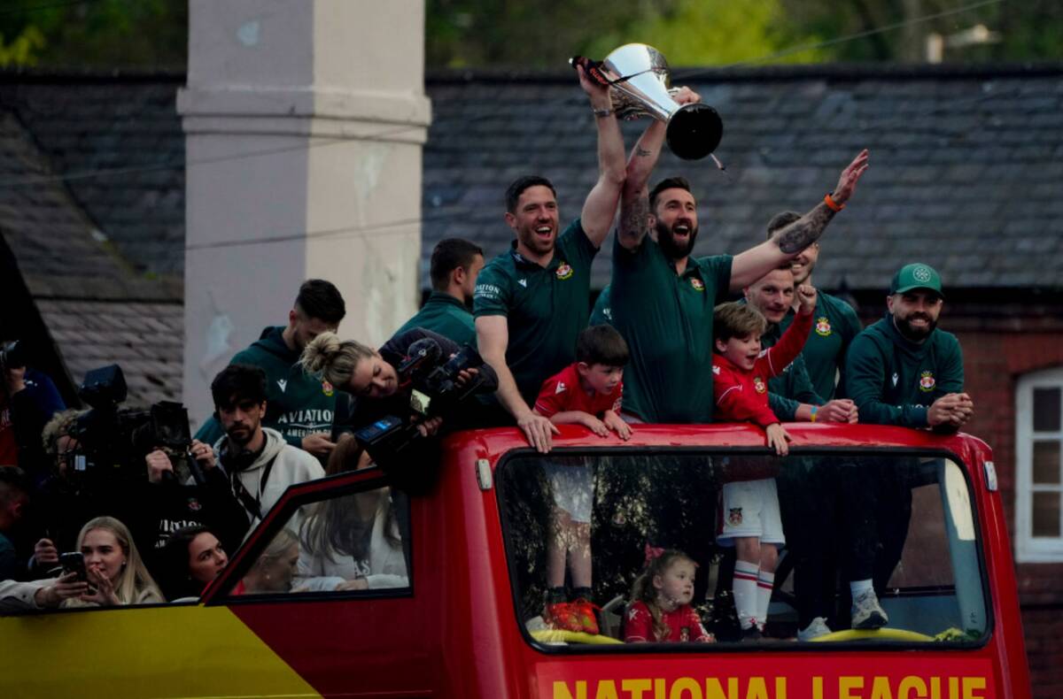 Members of the Wrexham FC soccer team ride on an open top bus as they celebrate promotion to th ...