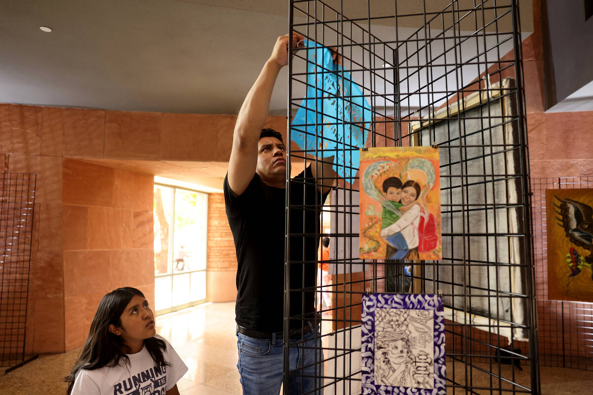 Meliton Monterrosas helps set up an exhibit by visiting Mexican artist Olegario Hernández Mend ...