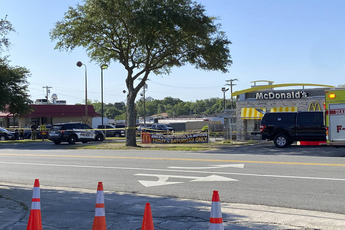 Police vehicles sit parked in front of a McDonald's restaurant as police investigate a shooting ...
