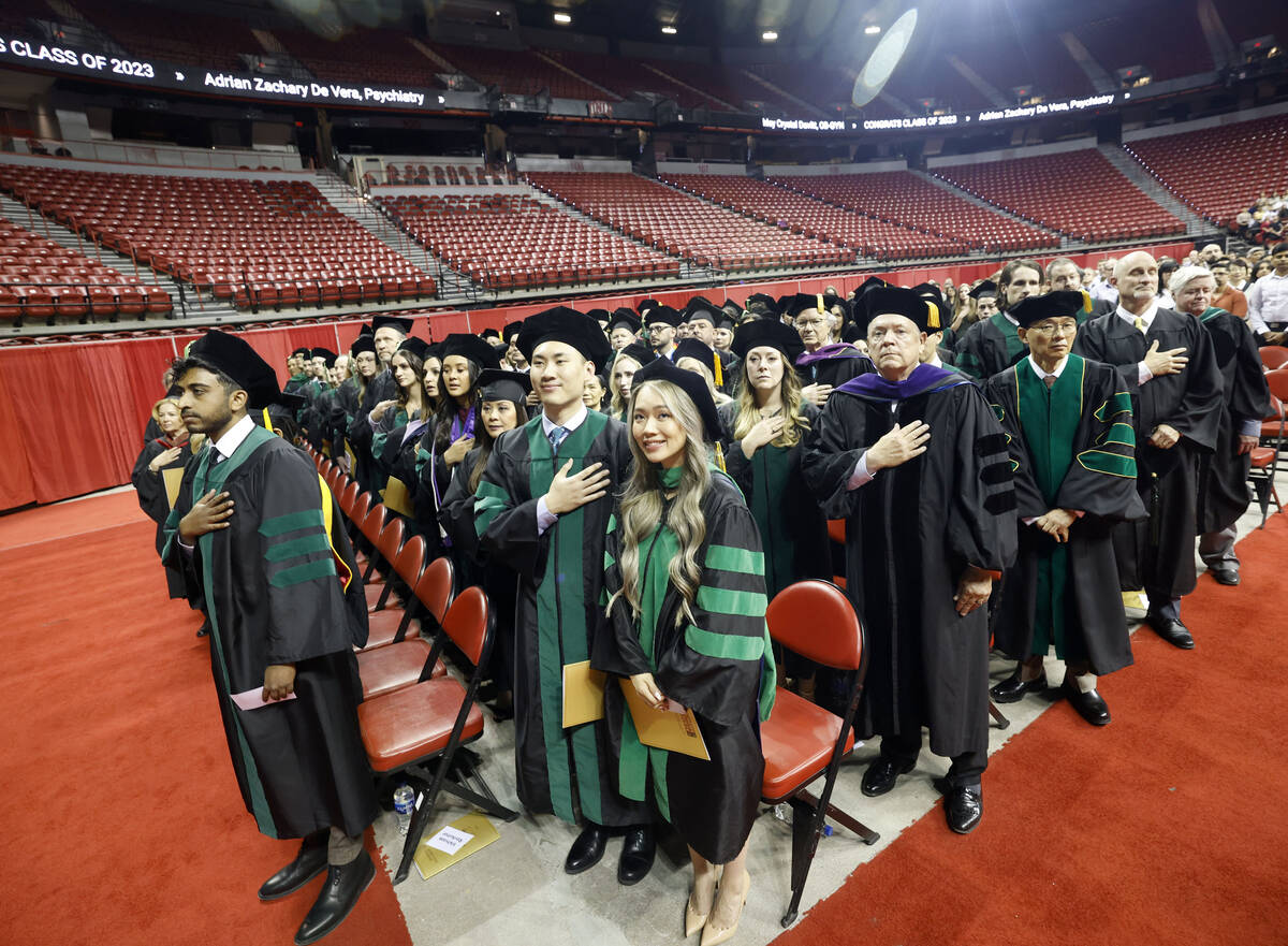 Students stand for the national anthem during the commencement and academic hooding ceremony of ...