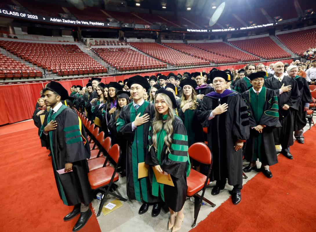 Students stand for the national anthem during the commencement and academic hooding ceremony of ...