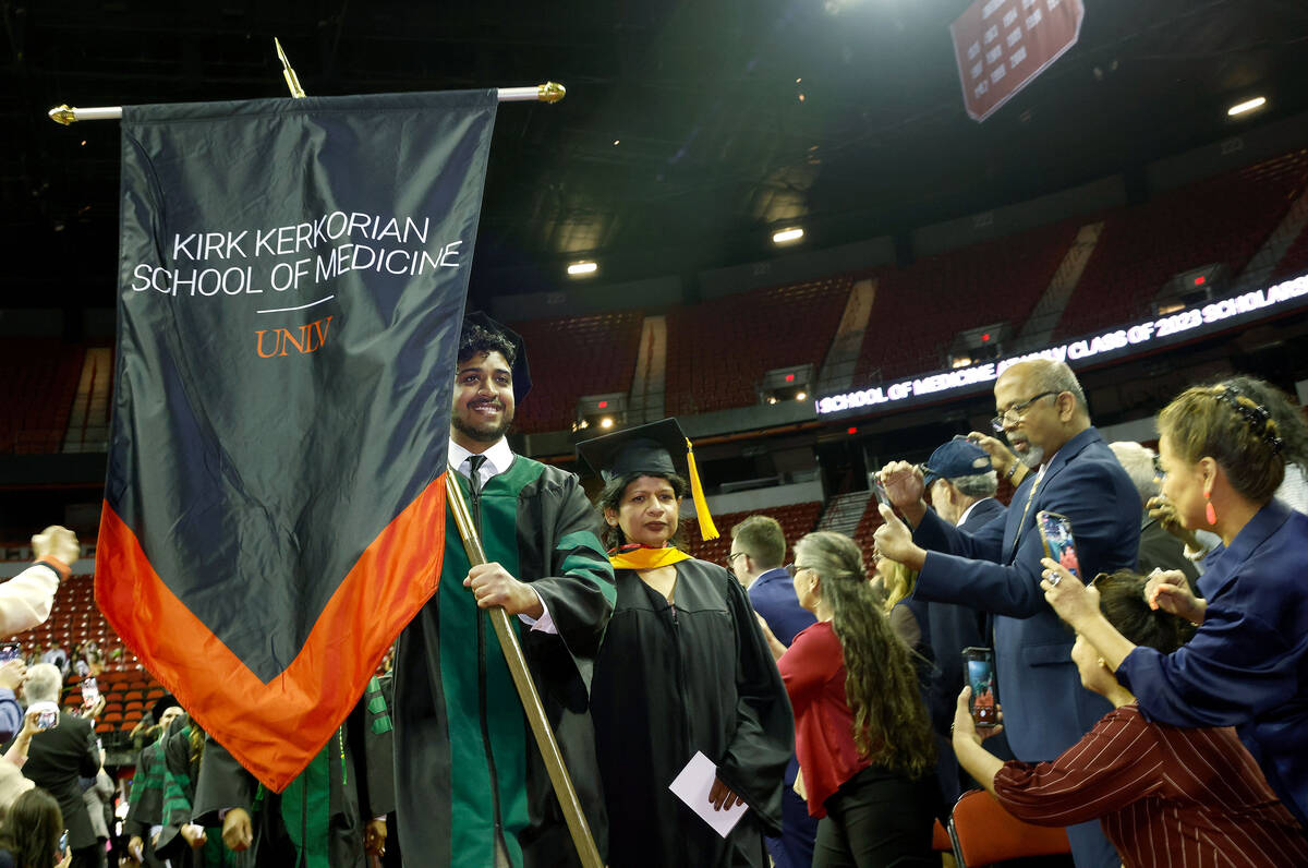Vishvaas Ravikumar holds a banner as students proceed to their seats during the commencement an ...