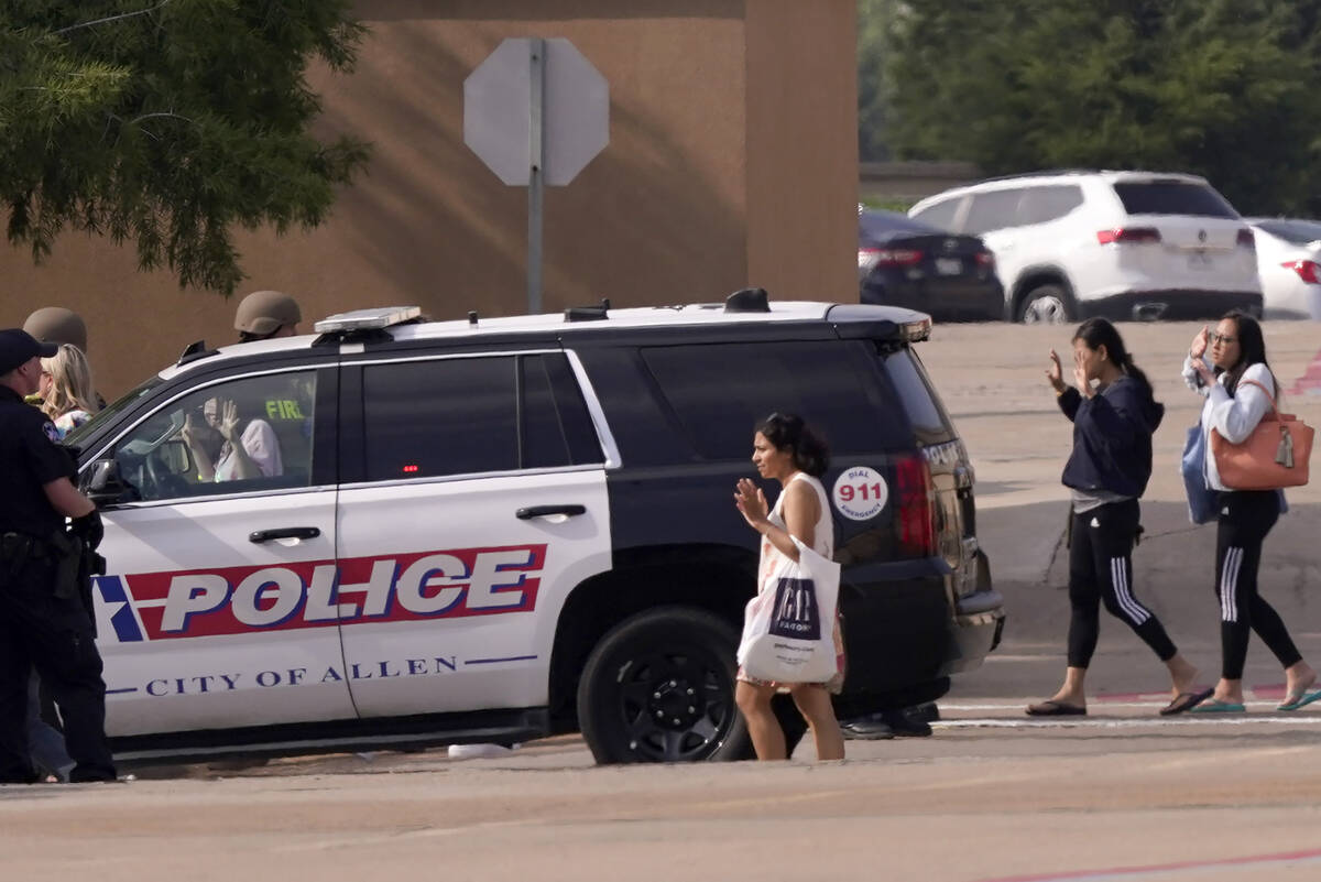 People raise their hands as they leave a shopping center after a shooting, Saturday, May 6, 202 ...