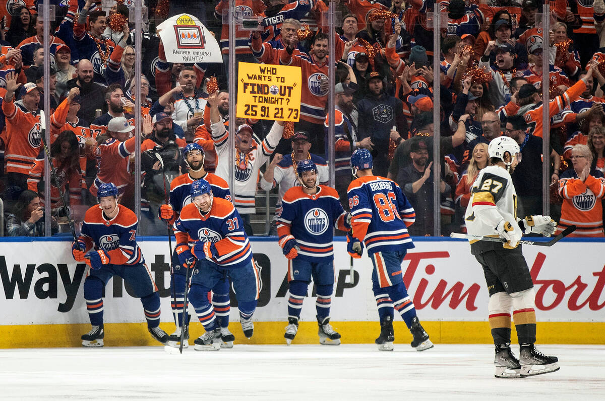 Vegas Golden Knights' Shea Theodore (27) skates past as the Edmonton Oilers celebrate a goal by ...