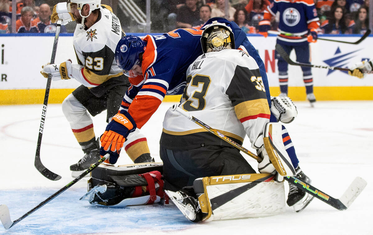 Edmonton Oilers' Klim Kostin (21) crashes into Vegas Golden Knights goaltender Adin Hill (33) d ...