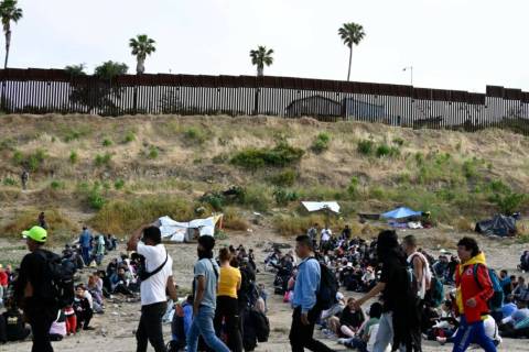 Asylum seekers wait between the double fence on U.S. soil along the U.S.-Mexico border near Tij ...