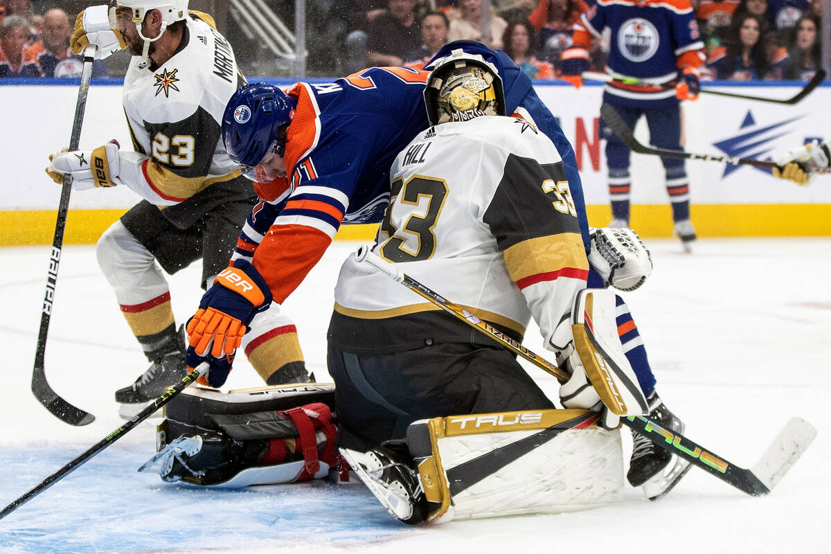 Edmonton Oilers' Klim Kostin (21) crashes into Vegas Golden Knights goaltender Adin Hill (33) d ...