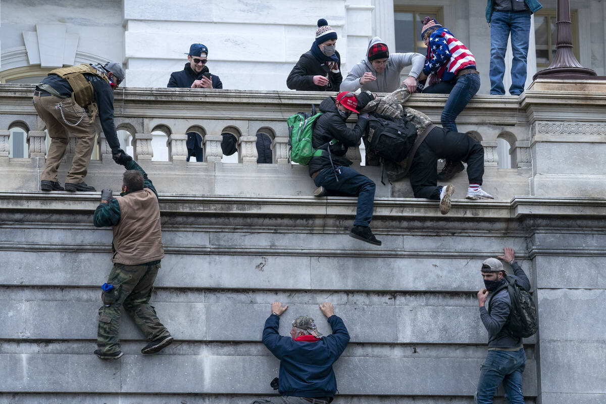 FILE - Rioters loyal to President Donald Trump climb the west wall of the the U.S. Capitol, Jan ...