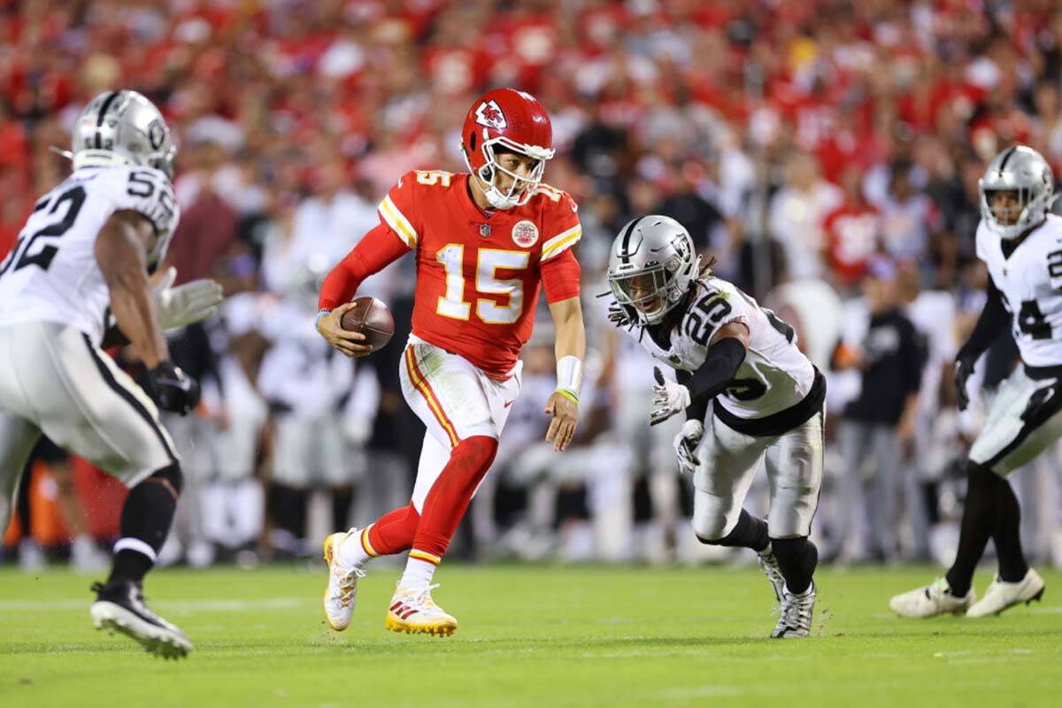 Kansas City Chiefs quarterback Patrick Mahomes (15) runs the ball under pressure from Raiders l ...