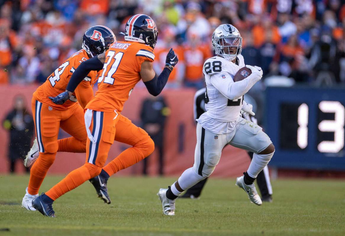 Raiders running back Josh Jacobs (28) runs past Denver Broncos linebacker Jacob Martin (54) and ...