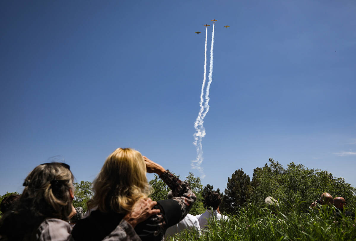 Family and friends watch a fly over in honor of Air Force Col. James Abraham at his funeral at ...