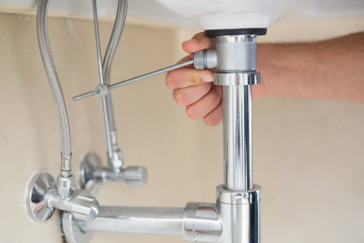 Extreme Close up of a plumber's hand and washbasin drain.