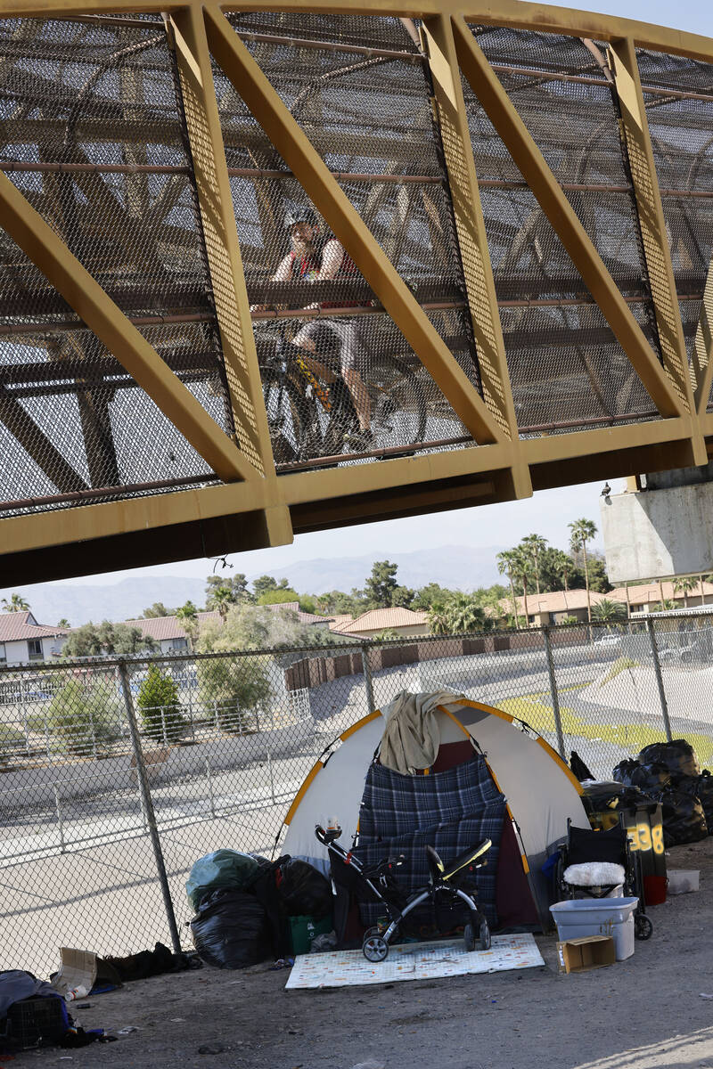 A man rides a bike on a pedestrian bridge over East Desert Inn Road, Thursday, May 11, 2023, i ...