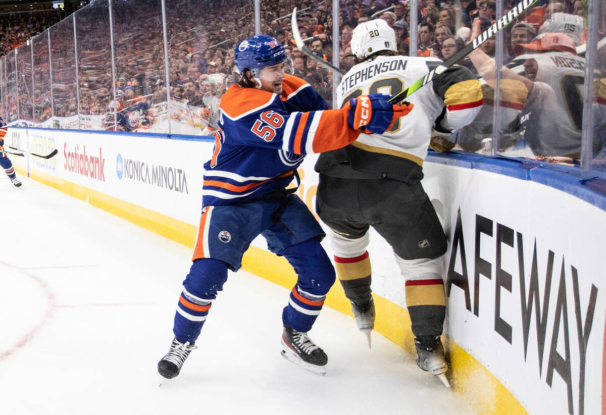 Vegas Golden Knights' Chandler Stephenson (20) is checked into the boards by Edmonton Oilers' K ...