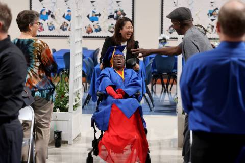 Graduate Allie Stokes walks in the processional with her teacher Cindy Barrett as her father Le ...
