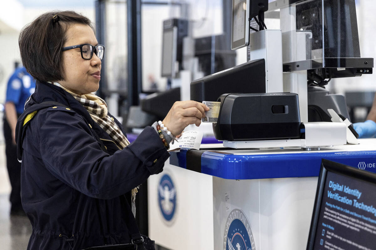 A traveler inserts her ID card while using the TSA's new facial recognition technology at a Bal ...