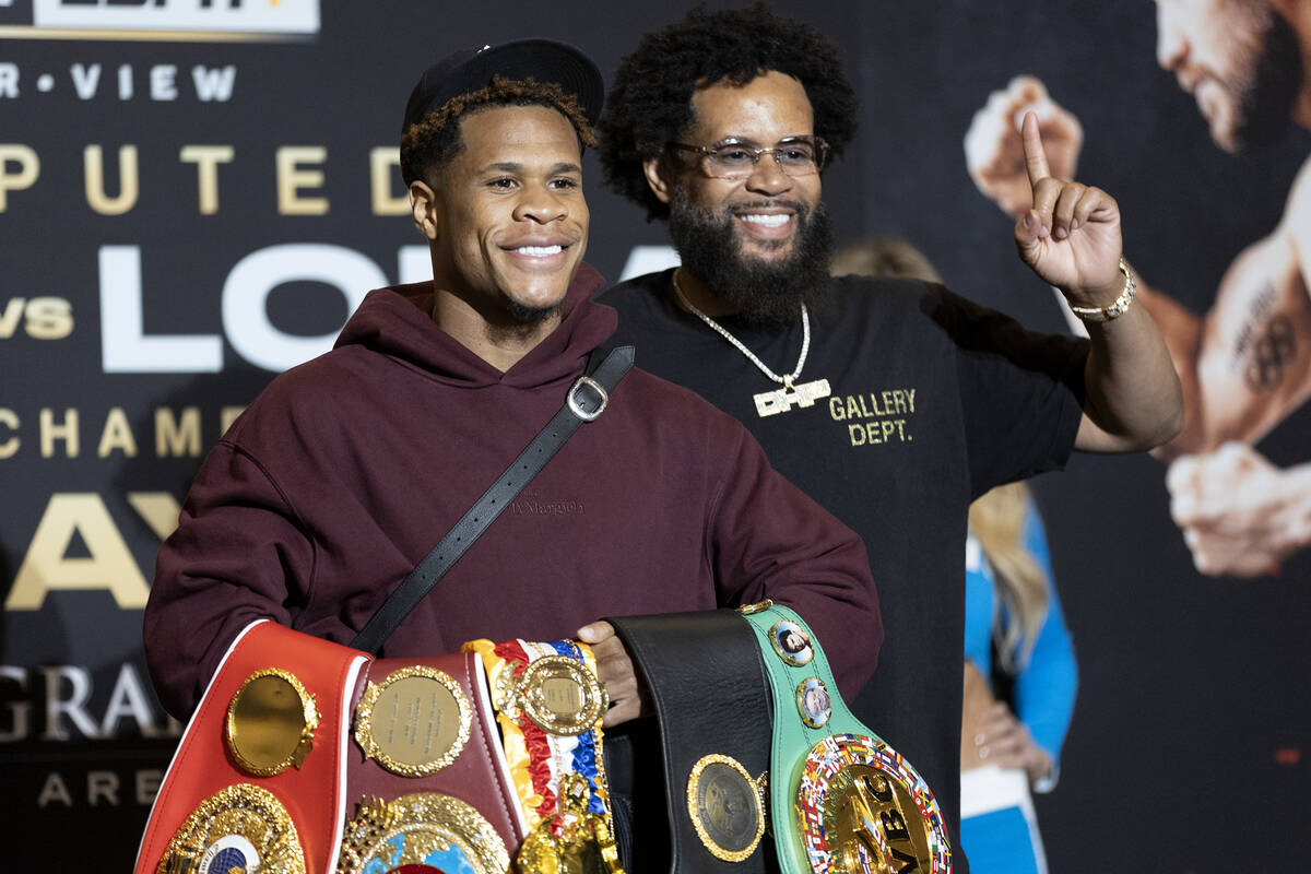 Devin Haney holds up his belts alongside his father and trainer, Bill Haney, after arriving to ...