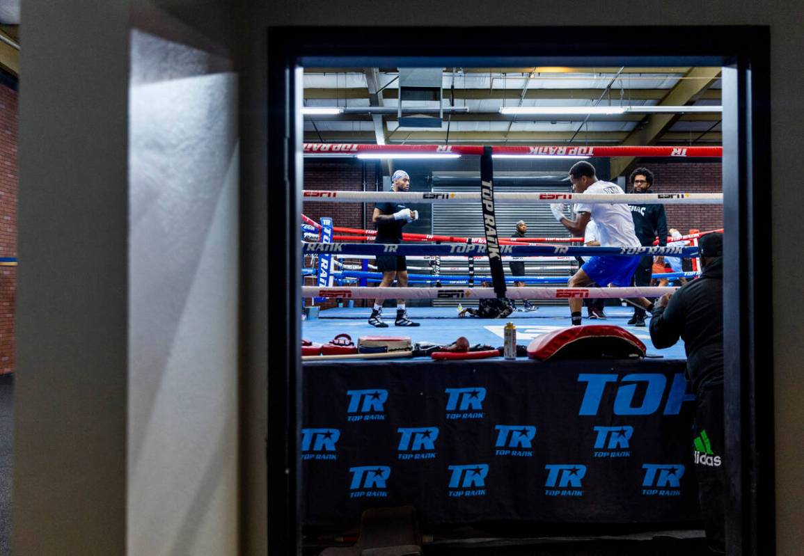 WBC lightweight boxer Devin Haney, center, shadow boxes in the ring as trainer Bill Haney, righ ...