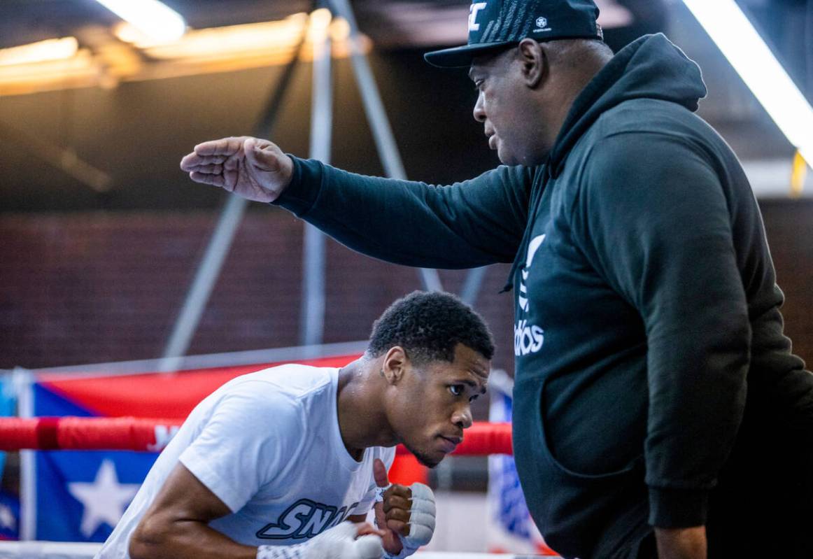 WBC lightweight boxer Devin Haney ducks under an arm by trainer Rodney Crisler in the ring duri ...