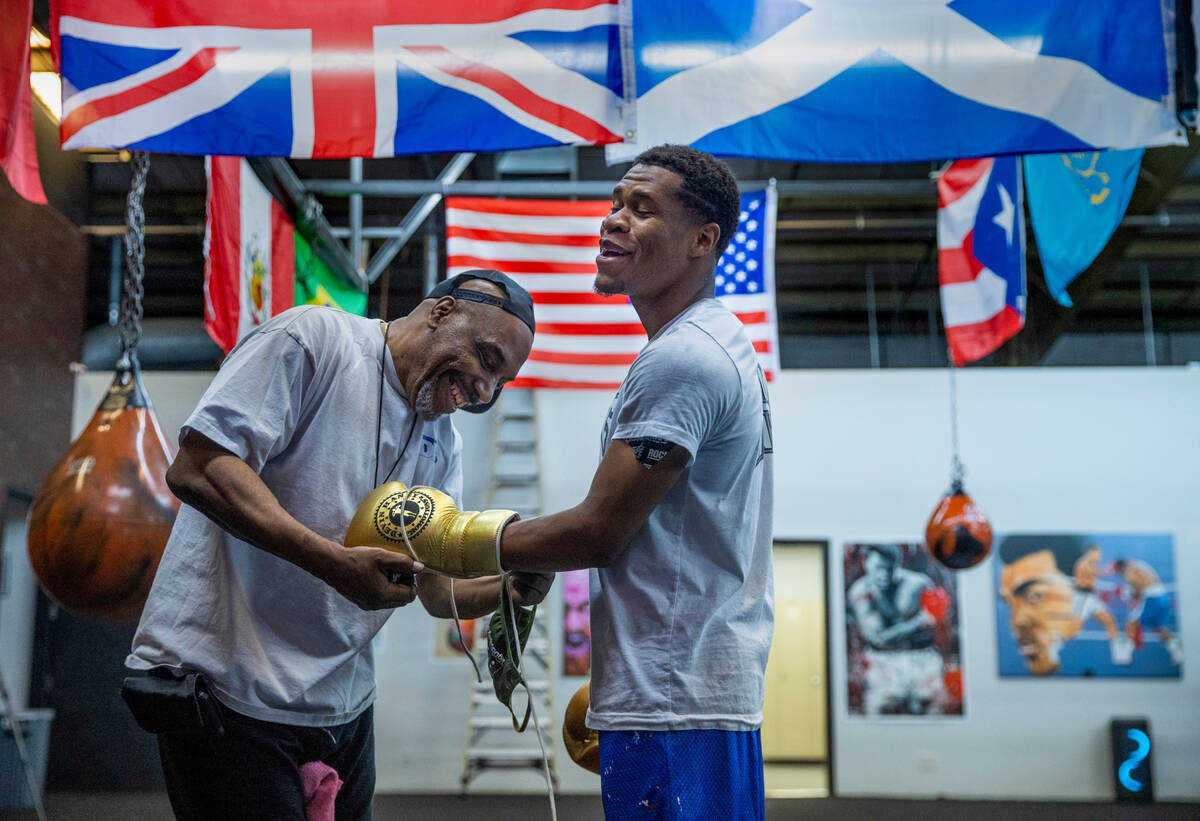 WBC lightweight boxer Devin Haney, right, is assisted with his gloves by trainer Darryl Flannig ...