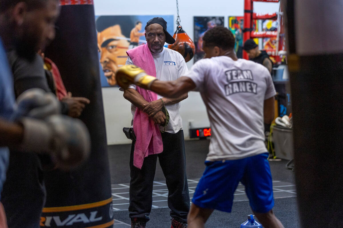 WBC lightweight boxer Devin Haney, right, throws a punch on a heavy bag as trainer Darryl Flann ...