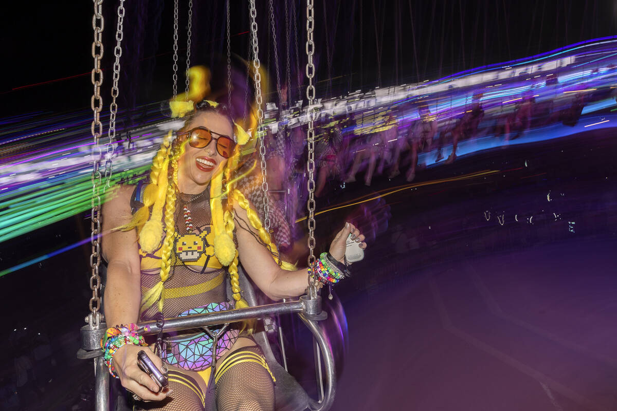Jess Olson, of San Diego, rides the swings during the second day of electronic dance music fest ...