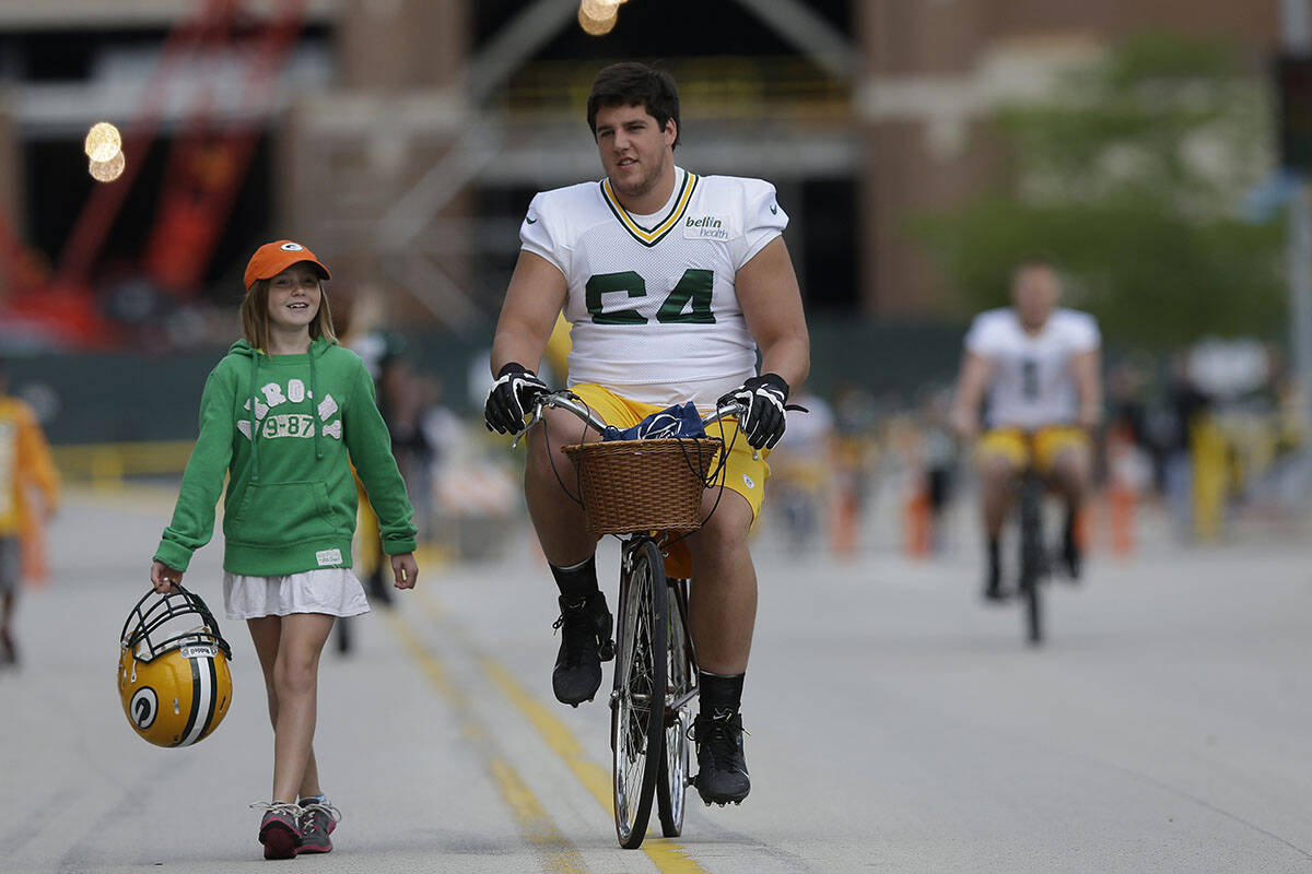 Green Bay Packers' Greg Van Roten rides a bike to NFL football training camp Saturday, July 27, ...