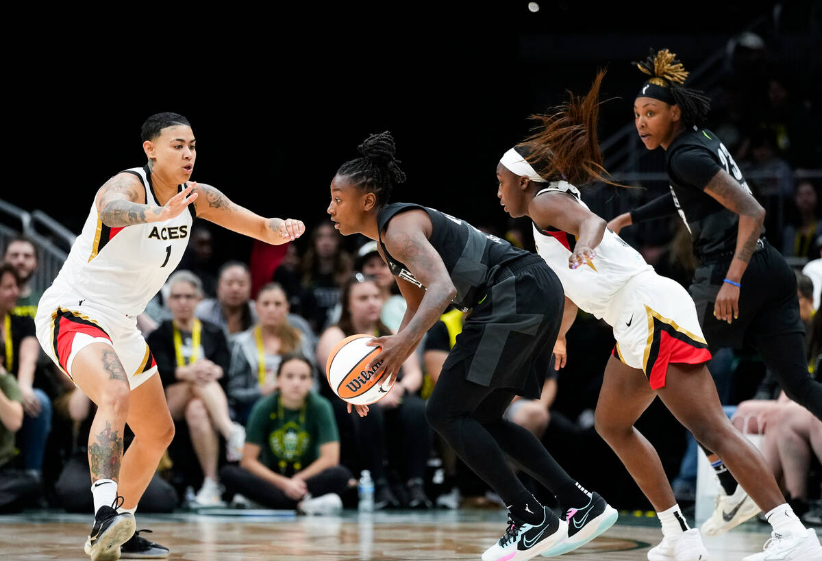 Seattle Storm guard Jewell Loyd, center, looks to drive around Las Vegas Aces guard Kierstan Be ...