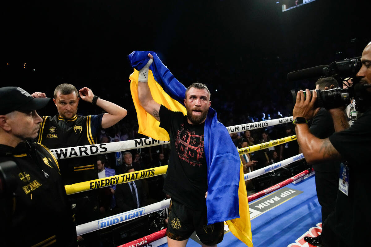 Vasiliy Lomachenko holds up his Ukrainian flag after an undisputed lightweight championship box ...