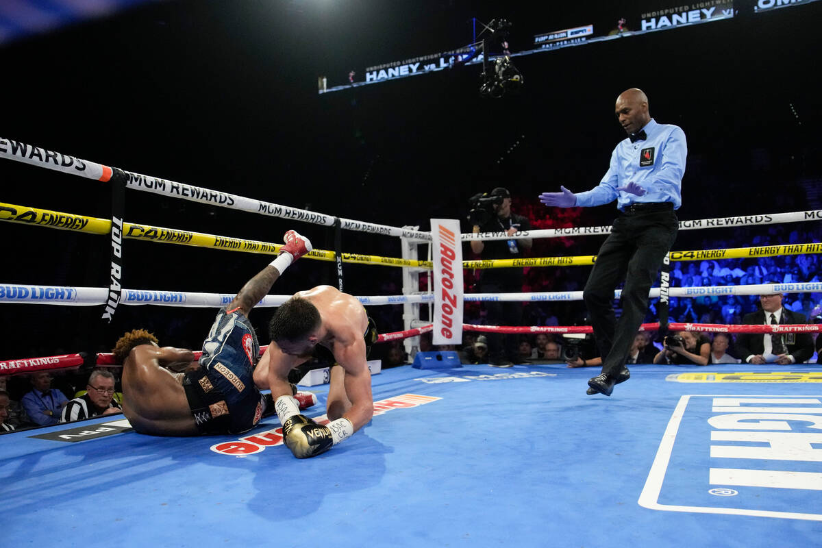 Devin Haney, left, and Vasiliy Lomachenko fall down in an undisputed lightweight championship b ...