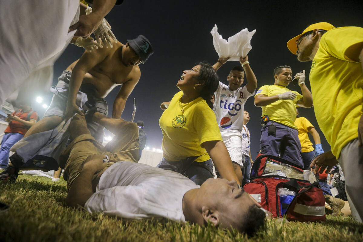 Rescuers attend an injured fan lying on the field of the Cuscatlan stadium in San Salvador, El ...