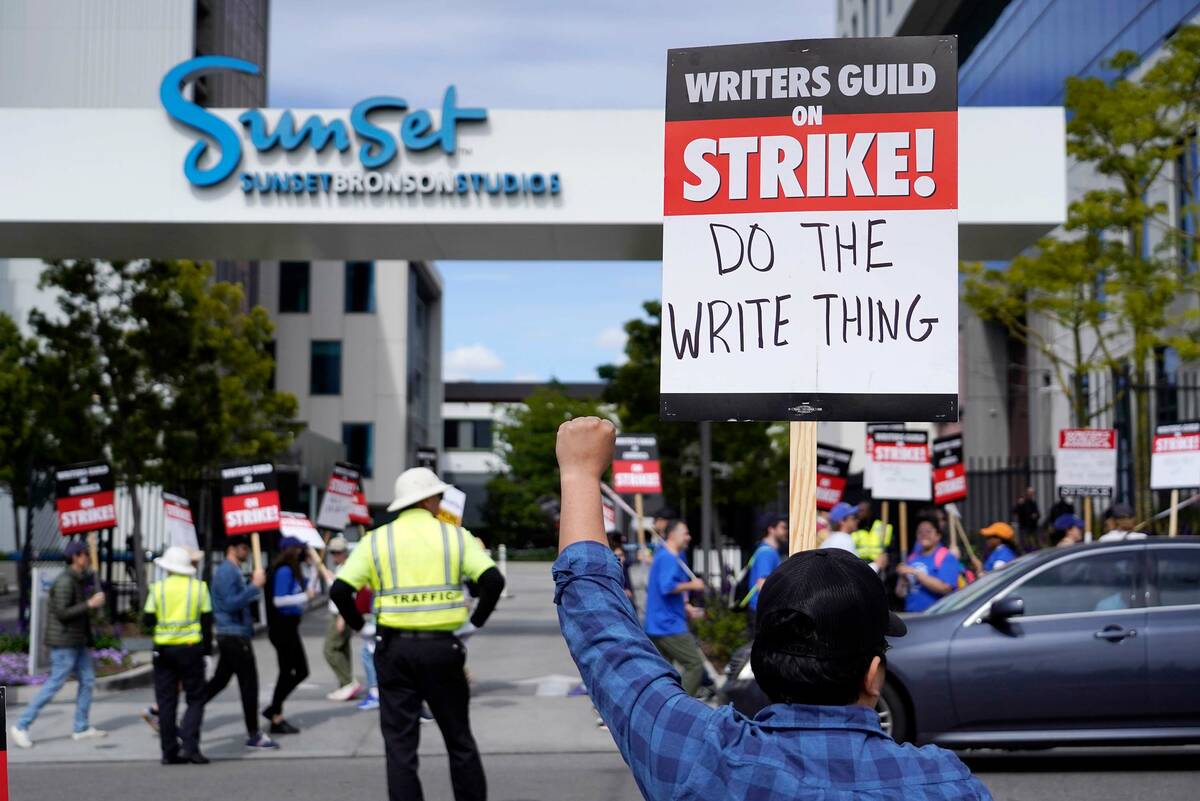 A demonstrator holds up a protest sign outside of Netflix offices on day two of a strike by the ...