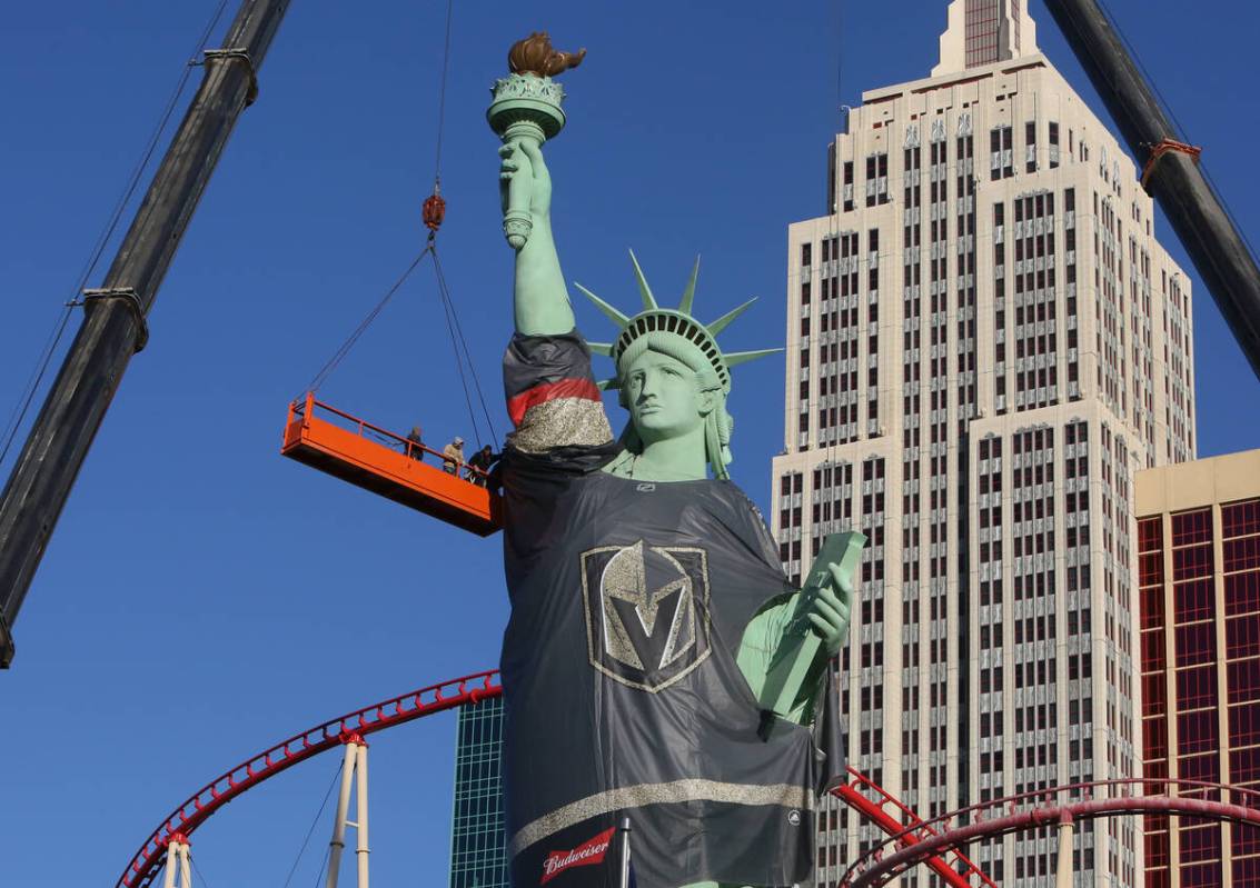 Workers install a Vegas Golden Knights jersey on the Statue of Liberty at New York New York on ...