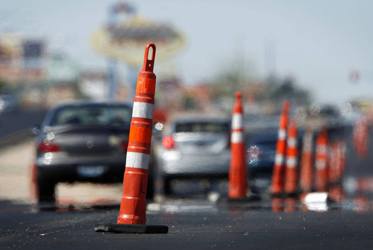 Heat rising from the pavement distorts the images of cars as they drive through road constructi ...