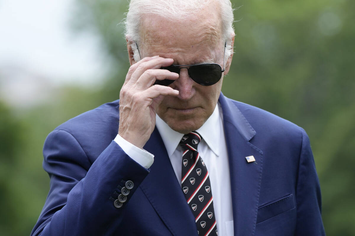 President Joe Biden removes his sunglasses as he walks to speak with reporters after returning ...