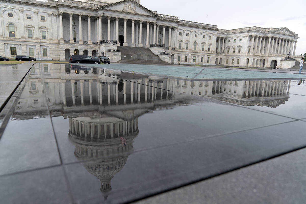 The U.S. Capitol is seen reflected in rain puddle on Monday, May 29, 2023, in Washington. After ...