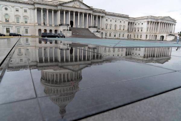 The U.S. Capitol is seen reflected in rain puddle on Monday, May 29, 2023, in Washington. After ...