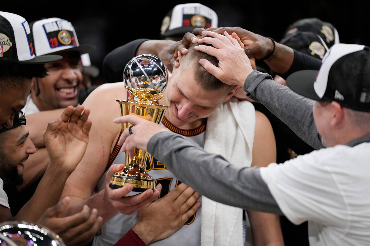 Denver Nuggets center Nikola Jokic is mobbed by teammates after accepting the series MVP trophy ...