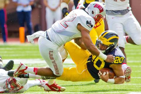 UNLV defensive back Peni Vea (42) tackles Michigan running back Drake Johnson (20) in the third ...
