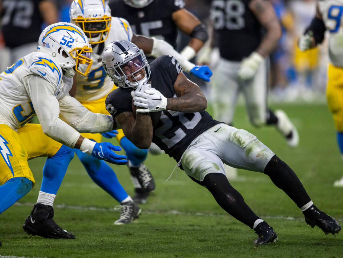 Raiders running back Josh Jacobs (28) falls into Los Angeles Chargers linebackers Khalil Mack ( ...
