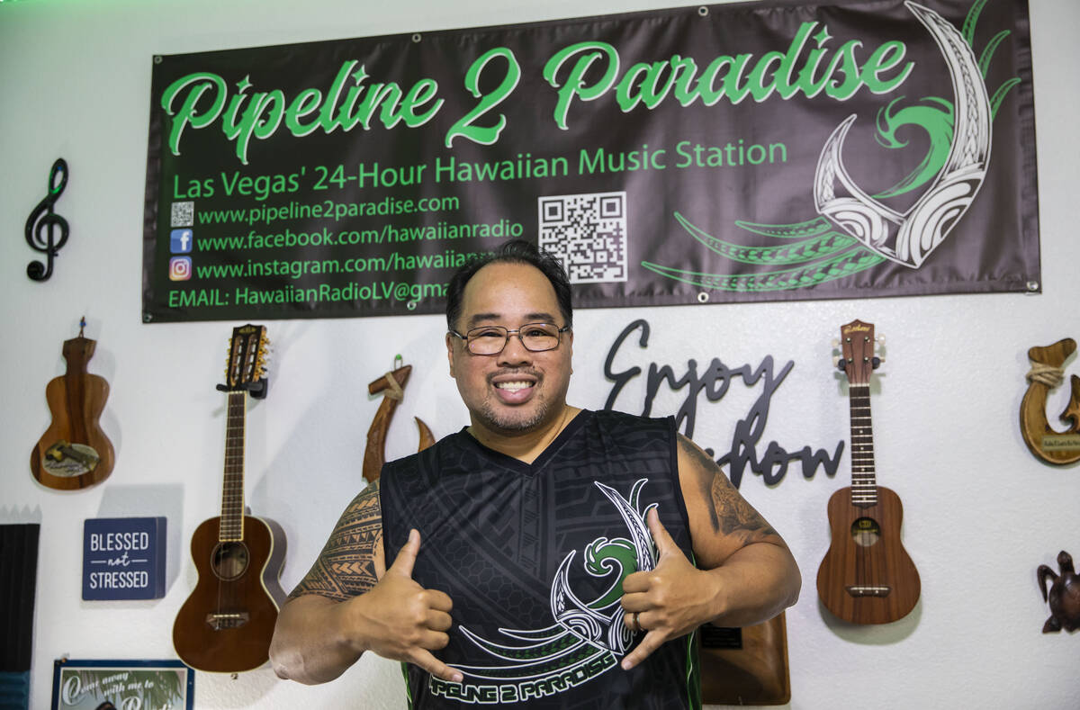 Paul Pu'ukani Sebala gives the shaka sign in front of a banner for his radio station, Pipeline ...