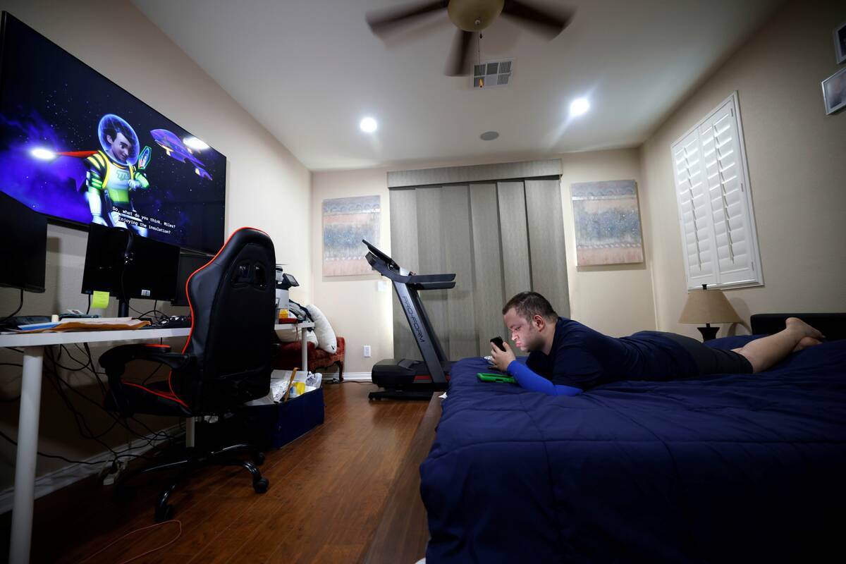 Samir Azarpira, 22, checks his cellphone as he watches a television in his house Thursday, June ...