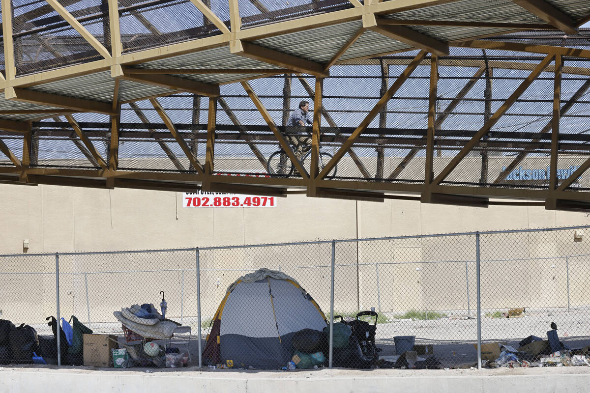 A man rides a bike on a pedestrian bridge over East Desert Inn Road, Thursday, May 11, 2023, i ...