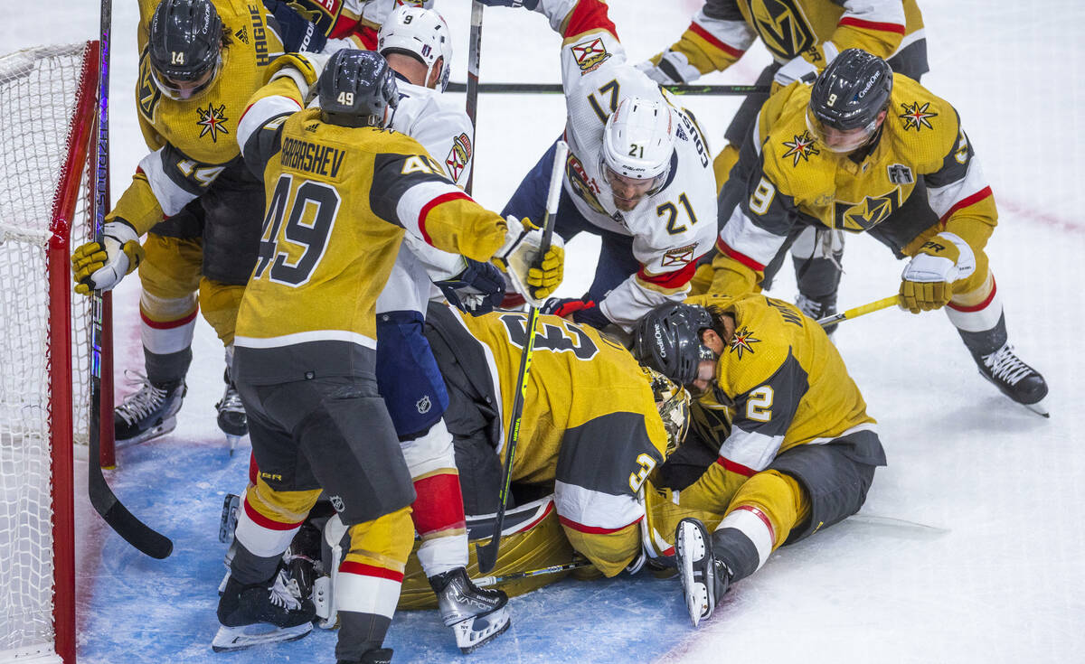 Golden Knights goaltender Adin Hill (33) and defenseman Zach Whitecloud (2) smother a shot with ...