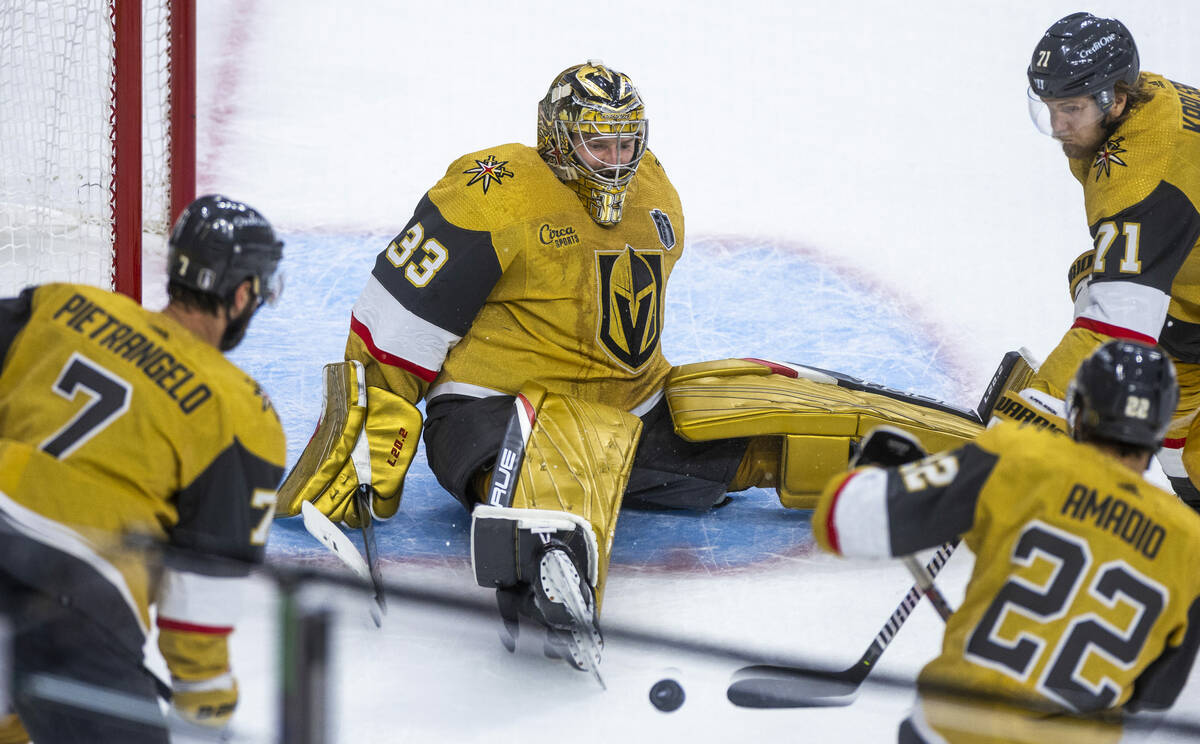 Golden Knights goaltender Adin Hill (33) looks to a loose puck with teammates during the first ...